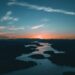 aerial photography of water beside forest during golden hour