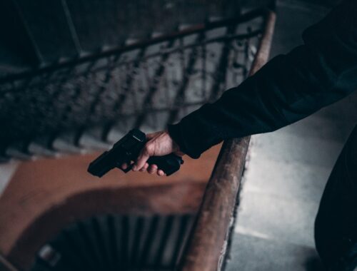 person in black jacket holding black gun